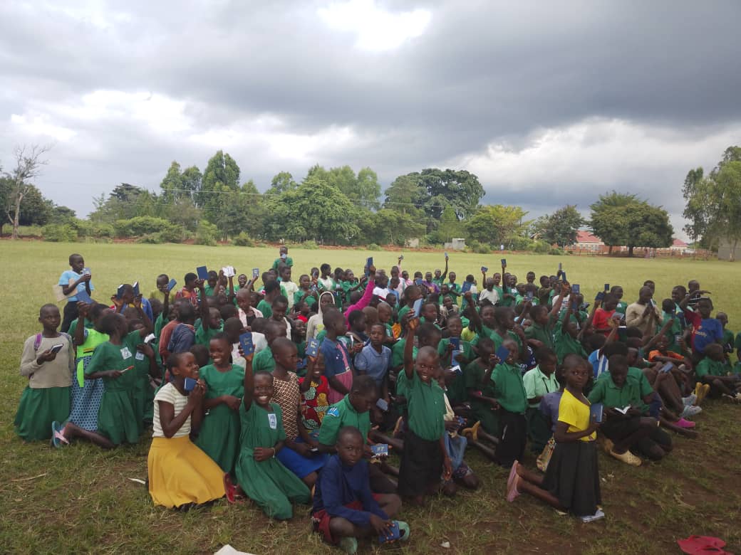 Students raising hands during scholastic supply distribution